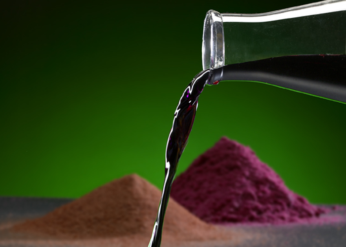 Purple metal solution being poured from a beaker